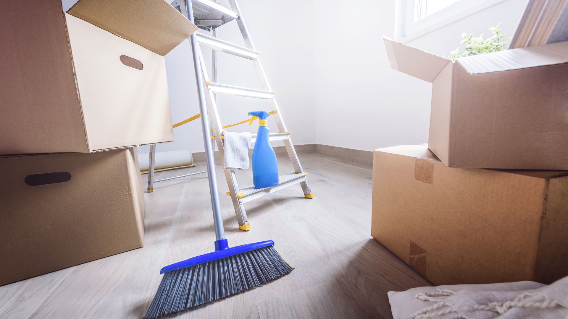 A room with boxes, a ladder, and a mop