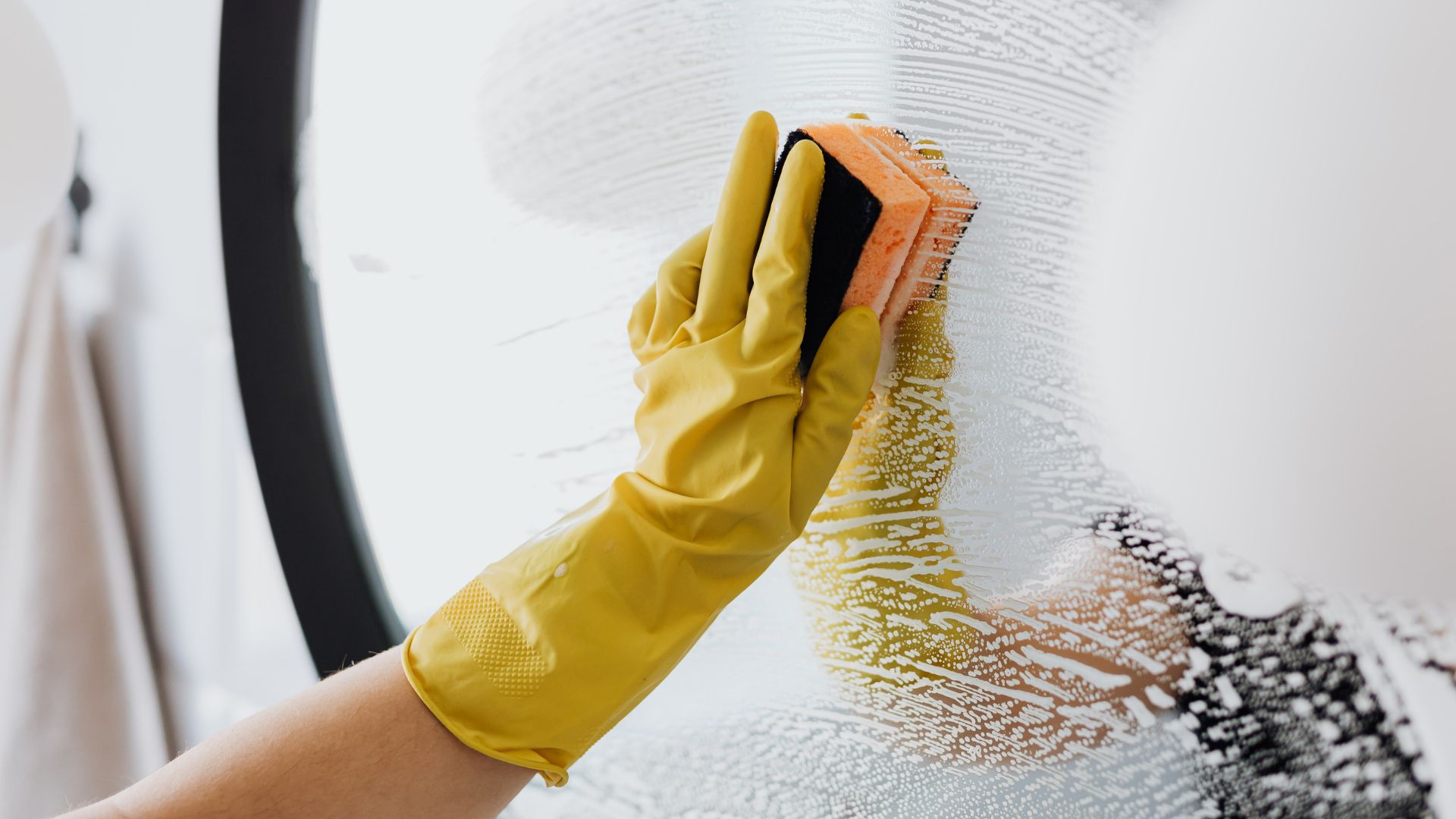 A person in yellow gloves and yellow gloves cleaning a wall