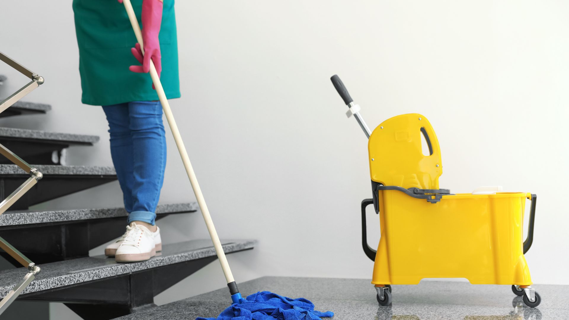 A person with a mop and a cleaning cart